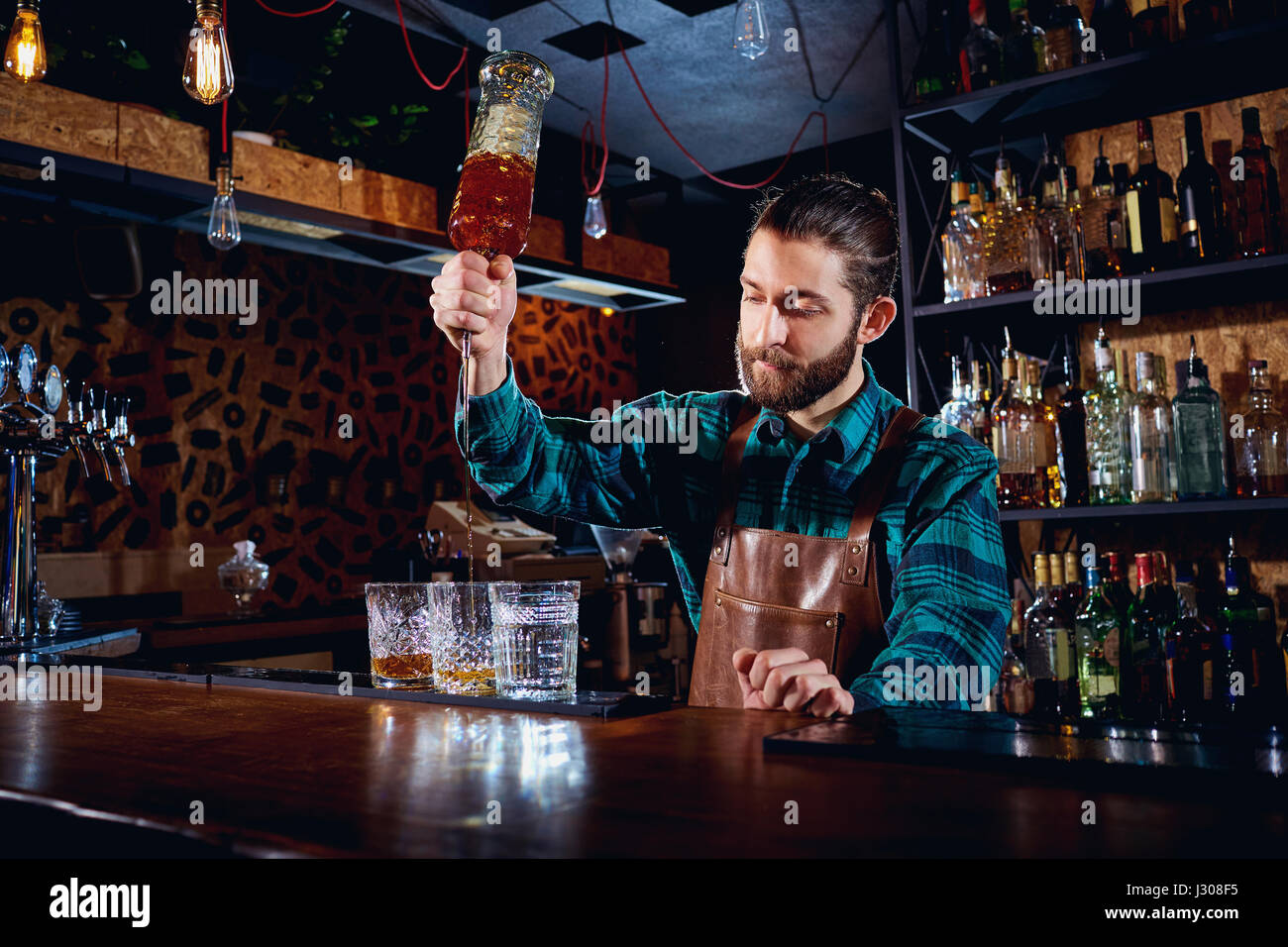 Das Barkeeper mit einem Bart gießt Alkohol in Gläser in einer bar Stockfoto