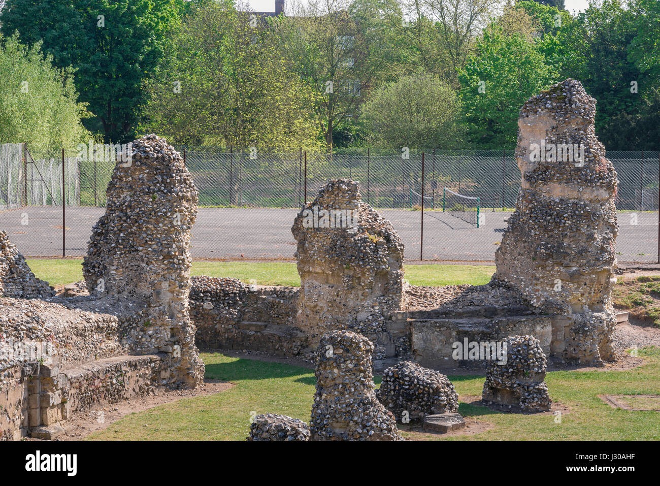 Bury St Edmunds Abbey Gardens, Detail der mittelalterlichen Abbey Ruins in Bury St Edmunds Abbey Gardens, mit dem alten Tennisplatz im Hintergrund, Großbritannien. Stockfoto