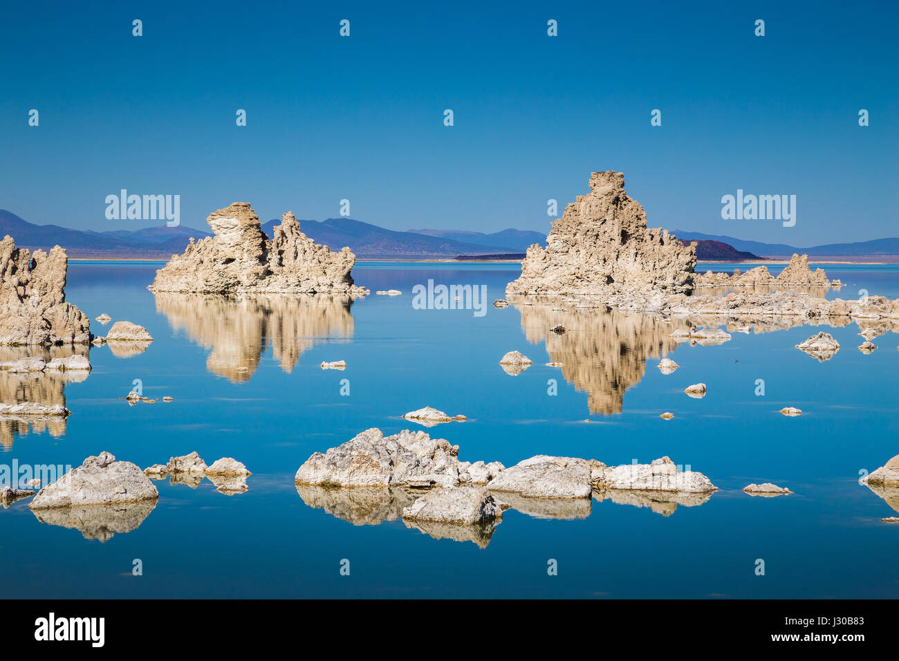 Klassische Ansicht der faszinierenden Tuffstein Felsformationen auf ruhige Wasseroberfläche des berühmten Mono Lake gespiegelt an einem schönen sonnigen Tag mit blauem Himmel im Sommer Stockfoto