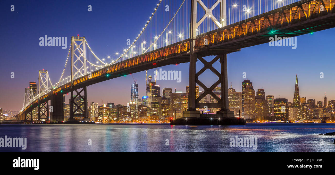 Klassische Panorama des berühmten Oakland Bay Bridge mit der Skyline von San Francisco beleuchtet in schöne post Sonnenuntergang Dämmerung, Kalifornien, USA Stockfoto