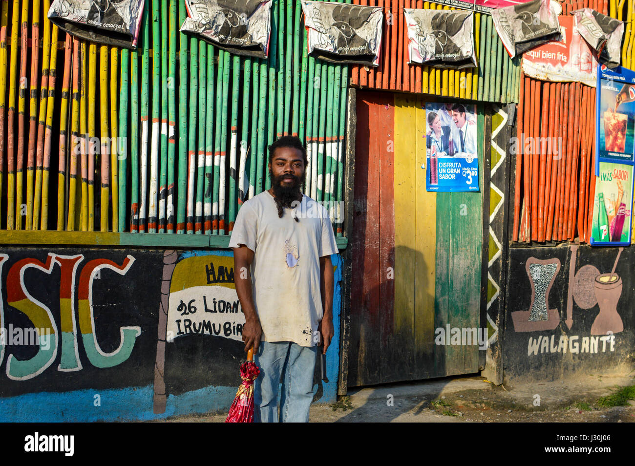 Garifuna Rasta Mann posiert mit einem Regenschirm in der einen Hand und einem Machetengriff in der anderen, in Livingston, Guatemala Stockfoto Garifuna Rasta Mann posiert mit einem Regenschirm in der einen Hand und einem Machetengriff in der anderen, in Livingston, Guatemala Stockfoto