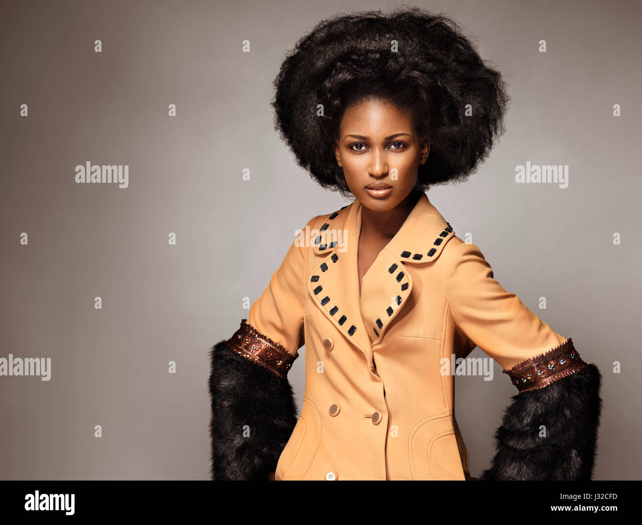 Führerschein und Fingerabdrücke auf MaximImages.com - Modeporträt einer schwarzen afroamerikanischen Frau, die einen orangefarbenen Mantel mit schwarzem Fell auf g trägt Stockfoto
