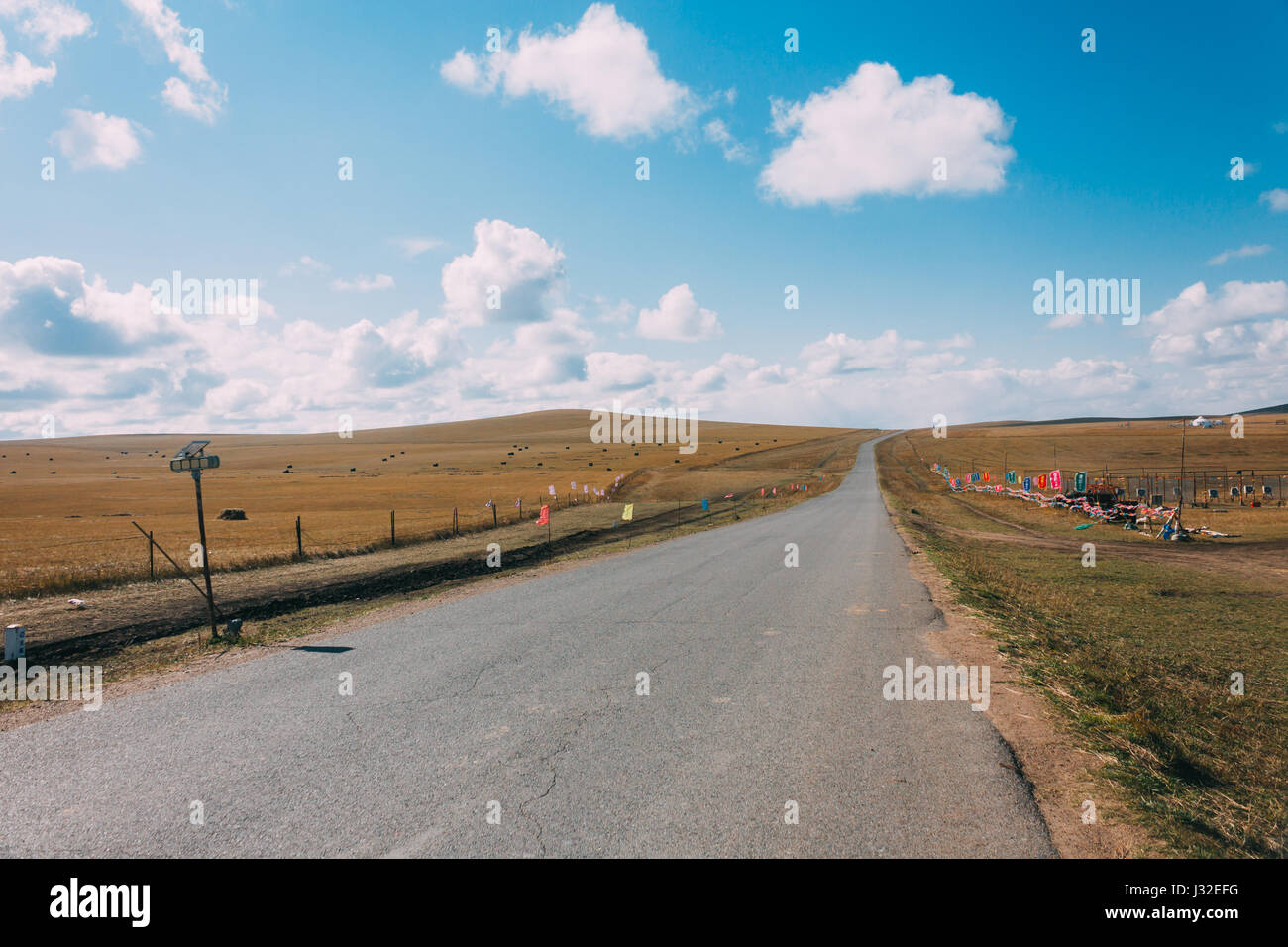 Leere Felder Straße in Grünland, blauen Himmel und weiße Wolken. Morgen. Innere Mongolei, Stockfoto