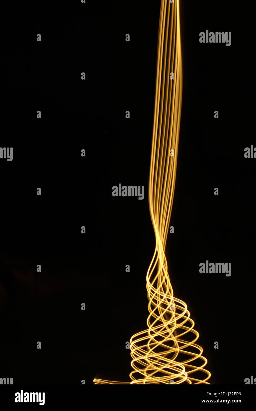 Lange Belichtung Foto von Neon farbe Gold in einer abstrakten wellenförmige Muster vor einem schwarzen Hintergrund. Licht Malerei Fotografie, abstrakte Farbe Stockfoto