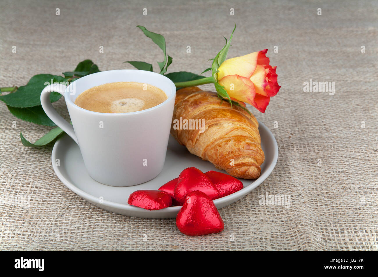 Kaffee, Croissants, Herz Schokolade in einer roten und rot-gelbe rose Stockfoto