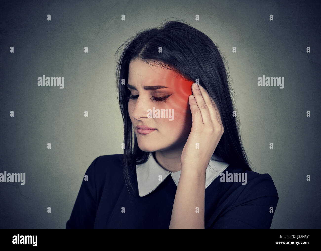 Tinnitus. Closeup, Seitenprofil krank weiblich mit Ohrenschmerzen berühren ihre schmerzhafte Kopf Tempel auf graue Wand Hintergrund isoliert rot gefärbt Stockfoto