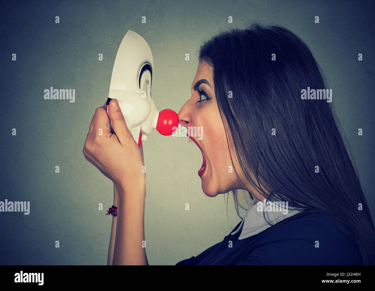 Böse Frau schreiend auf happy Clownsmaske Stockfoto