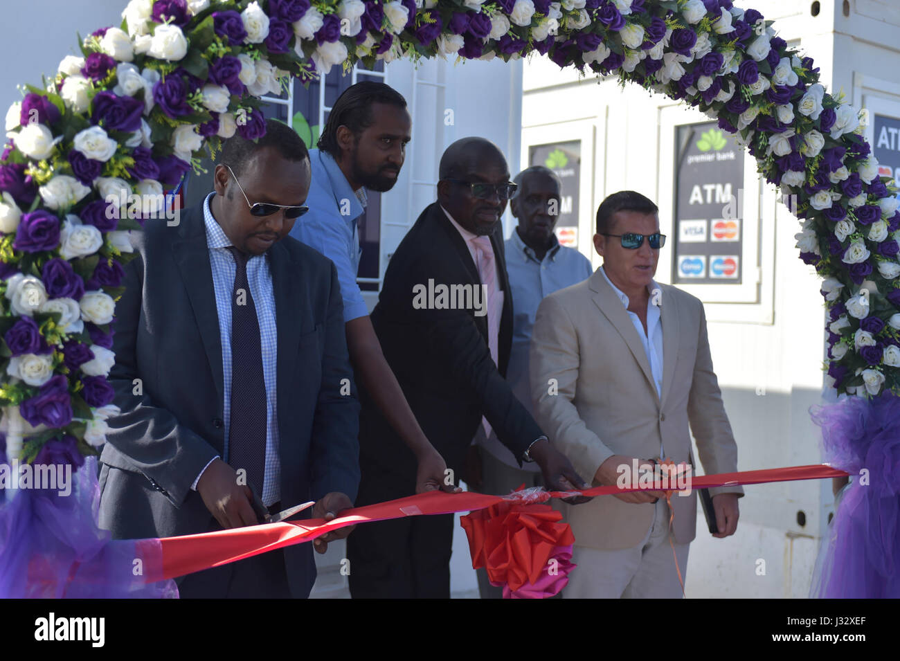 Minister für Arbeit und Soziales, Sala Jama und der CEO von SKA International, Mike Douglas, schneiden das Band zur Eröffnung einer neuen Filiale der Premier Bank in Mogadischu, Somalia, am 21. März 2017. AMISOM Foto Stockfoto