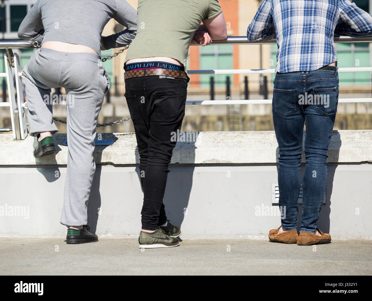 Rückansicht von drei jungen Männern stützte sich auf Geländer im Stadtzentrum von UK Stockfoto