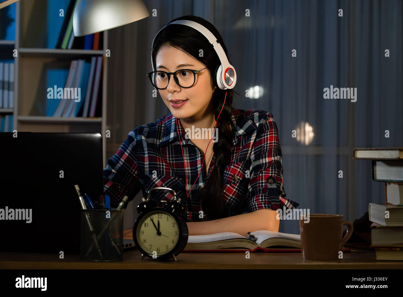 Hipster-Student studiert und während seines Studiums am Schreibtisch im Schlafzimmer abends Musik hören. Gemischte Rassen asiatische chinesische Modell. Stockfoto