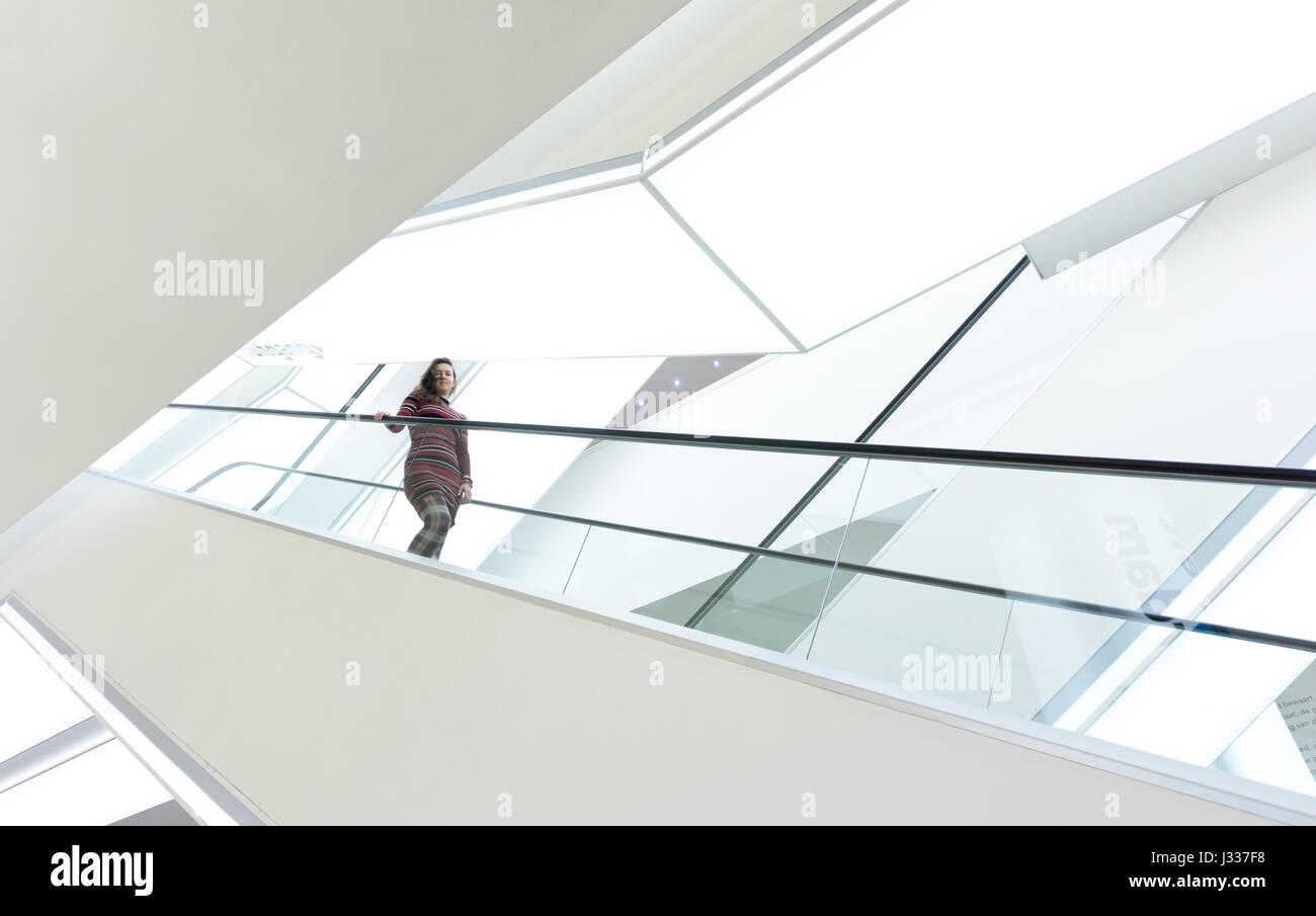 Frau auf einer Rolltreppe innen weiße vereinfachende Openbare Bibliotheek Amsterdam, Niederlande Stockfoto