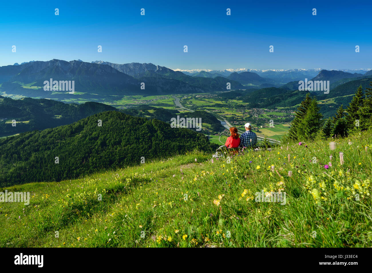 Zwei Personen sitzen auf einer Bank in Blumenwiese, Inntal im Hintergrund Kranzhorn, Chiemgauer Alpen, Tirol, Österreich Stockfoto