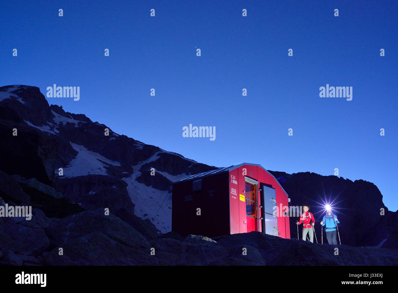 Zwei Personen Wandern in Richtung beleuchteten roten Biwak Biwak Molteni, Sentiero Roma, Bergell Reichweite, Lombardei, Italien Stockfoto