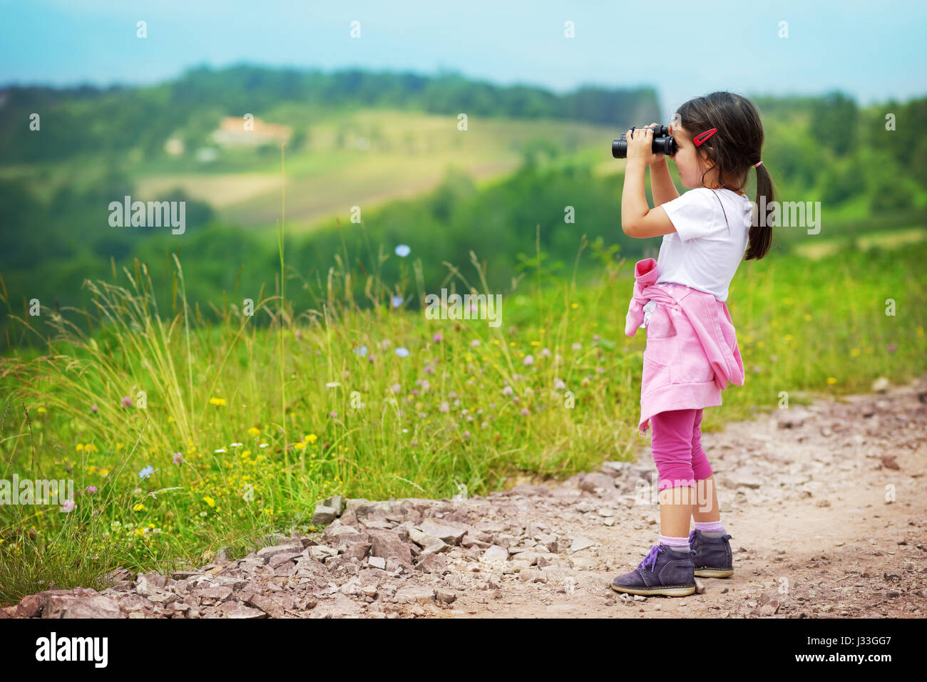 Kleines Mädchen Blick durch ein Fernglas im Freien. Sie ist verloren. Versucht, einen Weg nach Hause finden Stockfoto