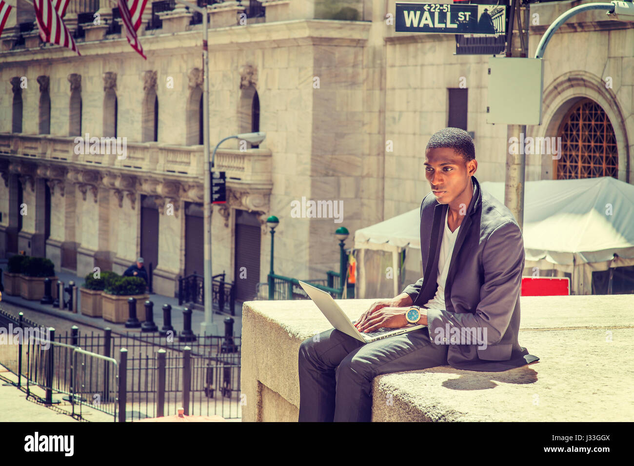 Young African American Mann Reisen, arbeitet in New York, sitzen auf der Straße von Vintage Büro Gebäude, lesen, arbeiten am Laptop-Computer. Wand-Str Stockfoto