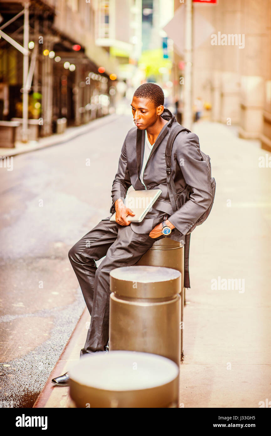 Young African American College Studenten reisen, Studium in New York, sollte Tragetasche, Laptop-Computer halten, sitzen auf Säule auf Vintage str Stockfoto