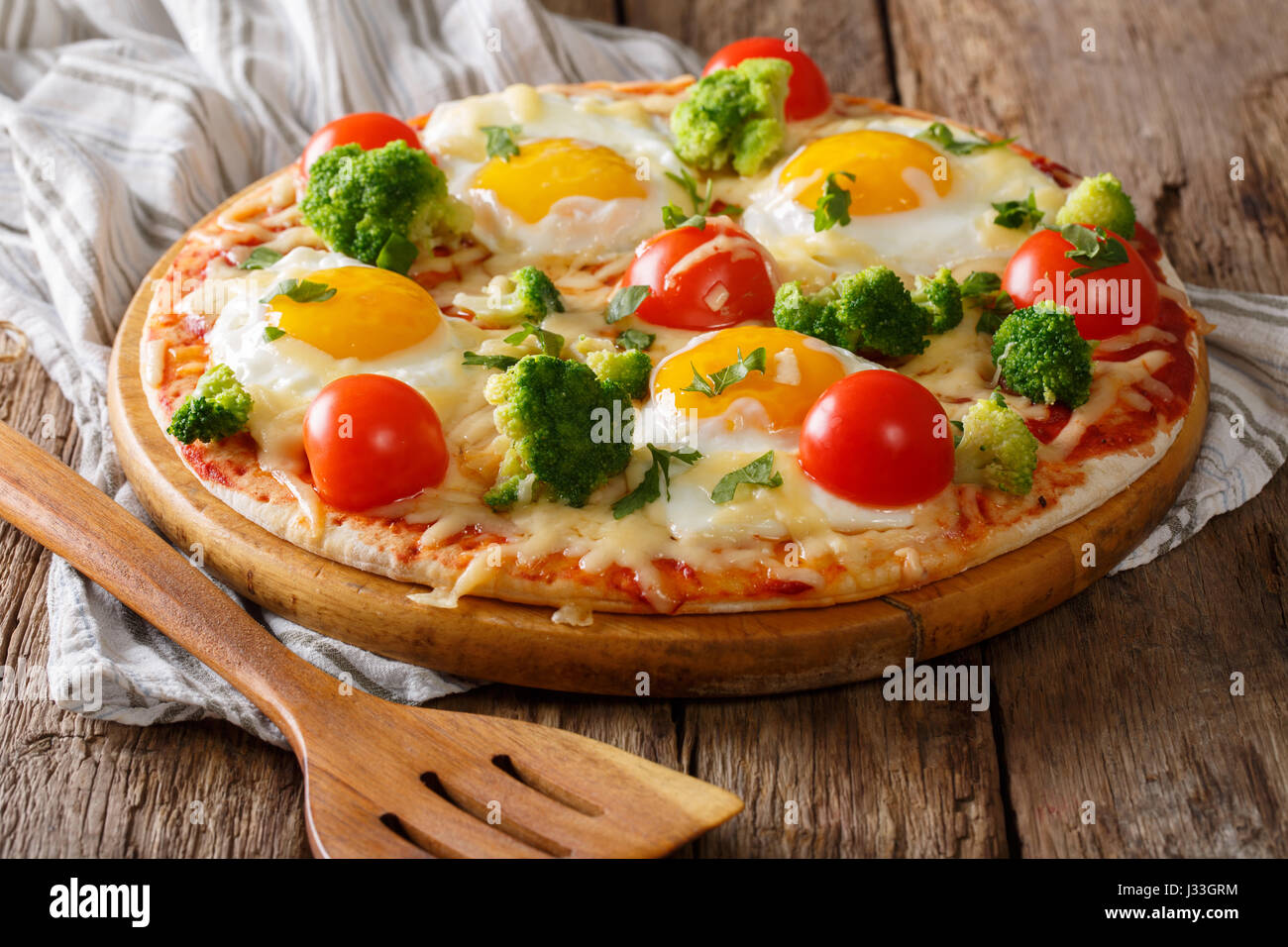 Pizza mit Eiern, Käse, Brokkoli, Tomaten und Kräutern Nahaufnahme auf dem Tisch. horizontale Stockfoto