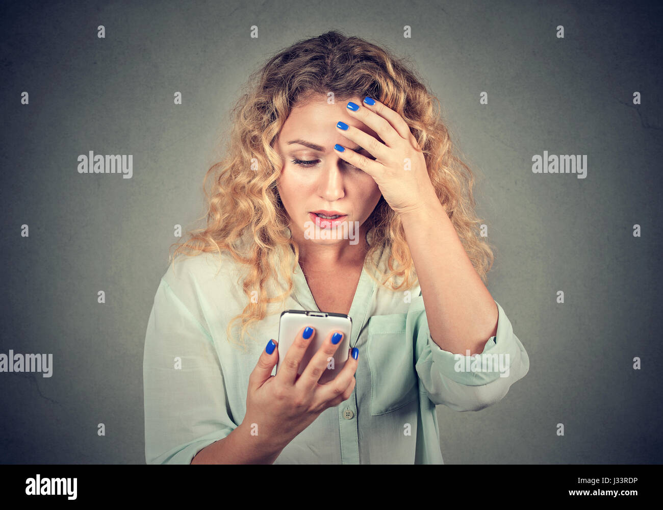 Verärgert gestresst Frau mit Handy angewidert mit Nachricht erhielt sie isoliert auf grauem Hintergrund. Menschliches Gesicht Ausdruck Emotion Gefühl Reaktion Stockfoto