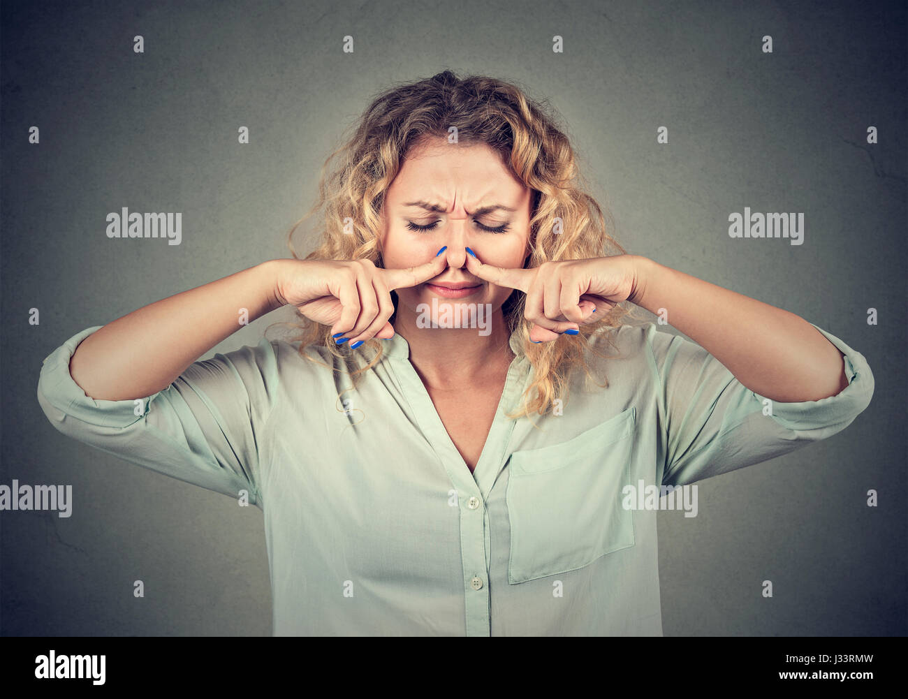 Closeup Portrait Frau Prisen Nase mit den Fingern sieht mit Ekel etwas schlechten Geruch auf graue Wand Hintergrund isoliert stinkt. Menschlichen Gesichtsausdruck Stockfoto