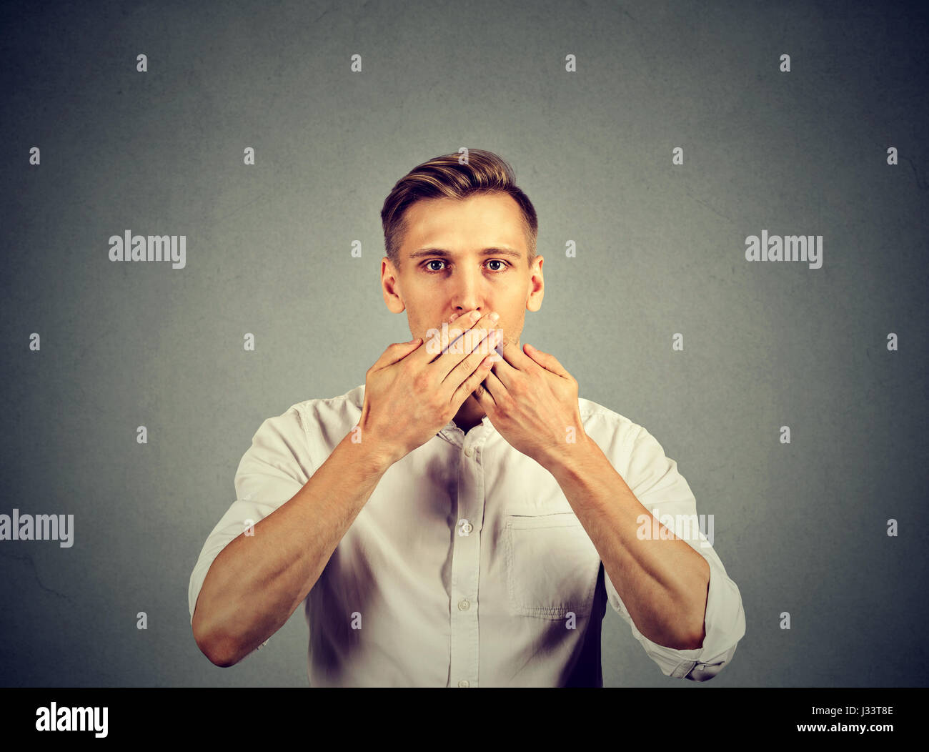 Mann mit Händen über seinen Mund, sprachlos auf graue Wand Hintergrund isoliert Stockfoto