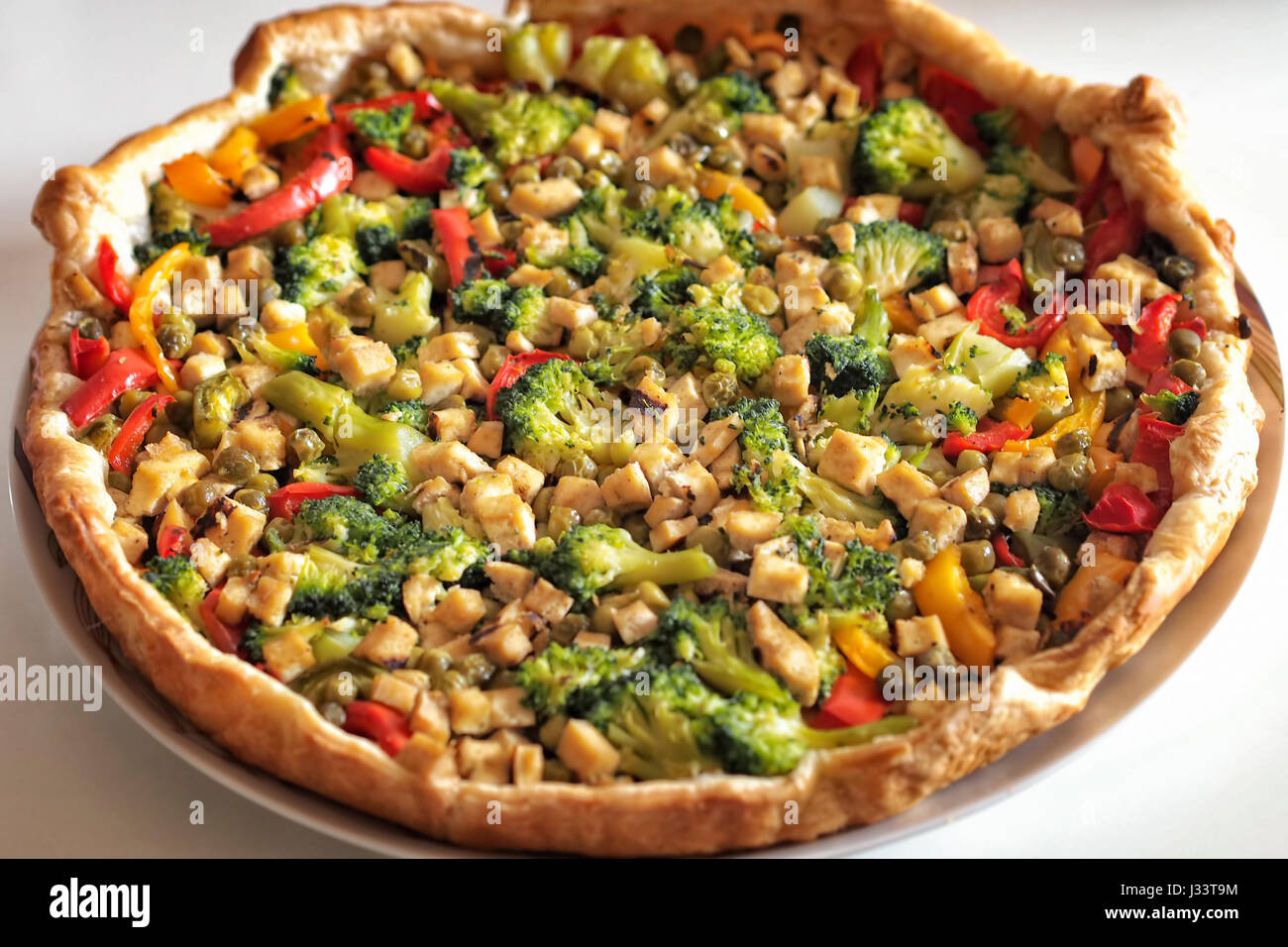 Hausgemachte Pizza mit geschnittenen Soja Tofu, Paprika, Brokkoli, Erbsen und Karotten Bio-Zutaten. Vegan und gesunde Ernährung. Stockfoto