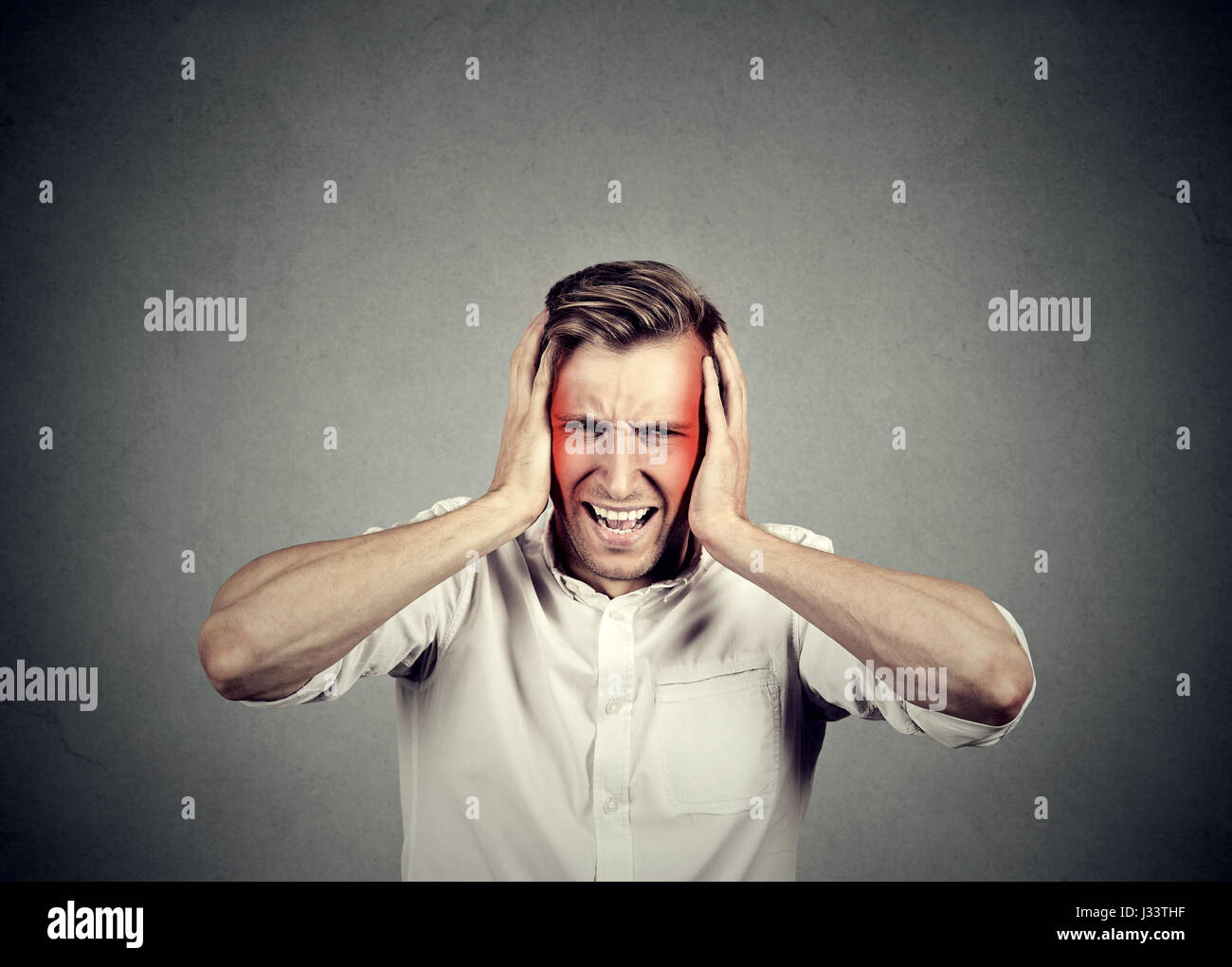 Mann mit Kopfschmerzen auf graue Wand Hintergrund isoliert Stockfoto