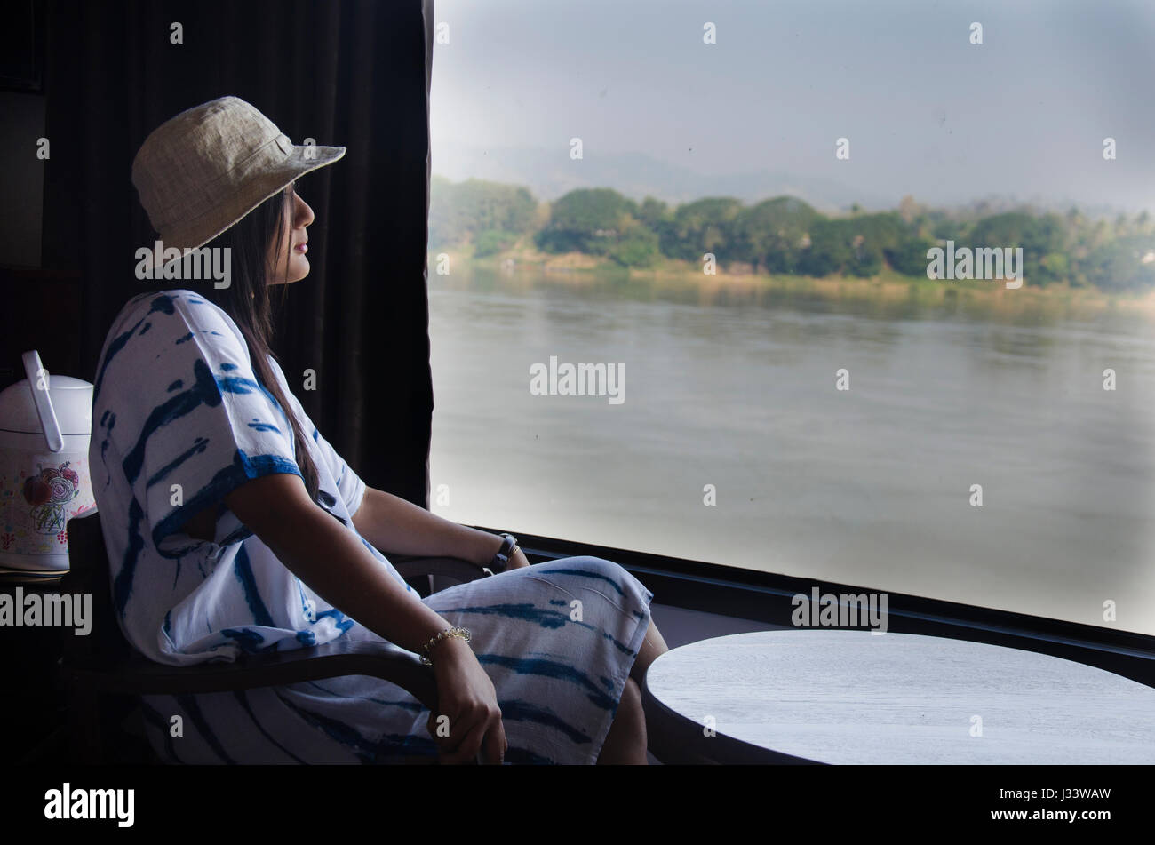 Allein thai-Frau sitzt auf dem Stuhl suchen anzeigen Landschaft und fließt der Fluss Mae Khong im Resorthotel in Chiang Khan in Loei, Thailand. Stockfoto