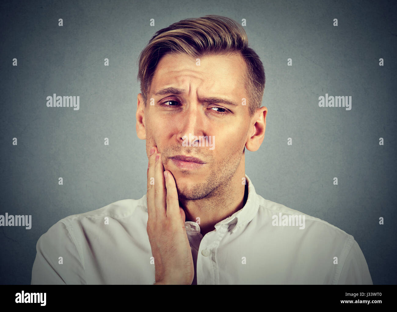 Porträt des jungen Mannes mit empfindlichen Zahn Schmerzen Krone Problem leiden, Schmerz, Berührung außen Mund mit der Hand auf grauem Hintergrund isoliert Stockfoto