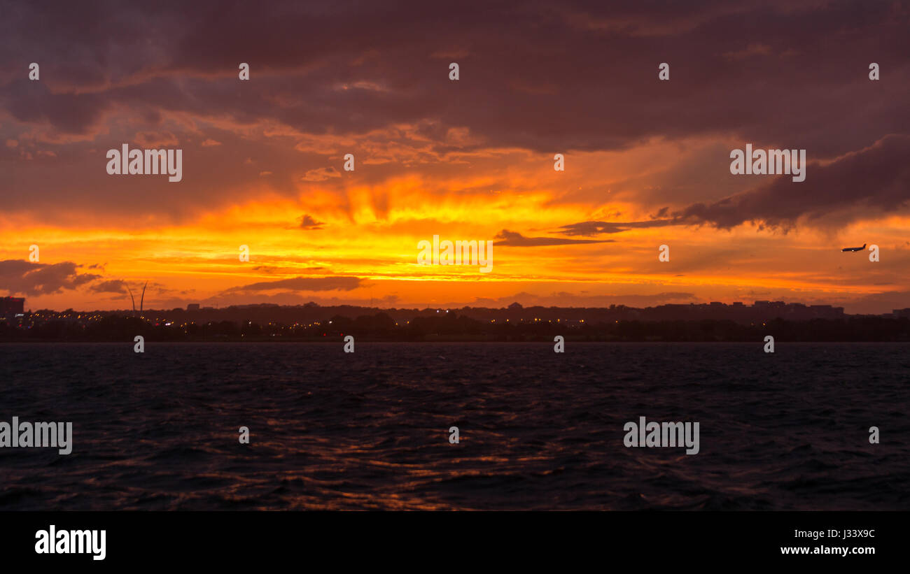 Eine leuchtende Orange, Sonnenuntergang und dämmerungsaktiv Strahlen erscheint am Himmel über dem Potomac-Fluss als Stürme bewegte sich durch, die Gegend von Washington D.C.. Stockfoto