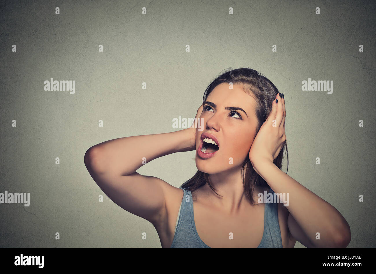 Closeup Portrait junge unglücklich betonte Frau für ihre Ohren aufhören, Lärm, es mir Kopfschmerzen isoliert auf graue Wand Backgr gibt, nachschlagen Stockfoto