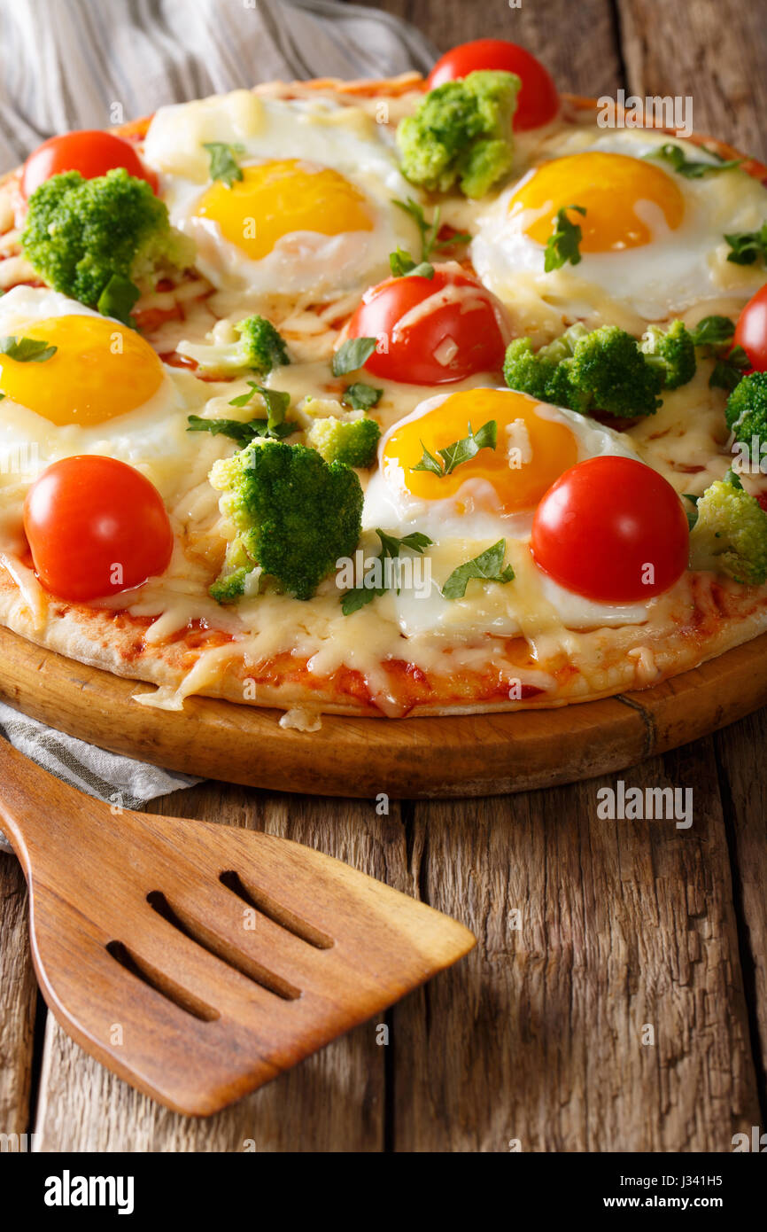 Schöne Pizza mit Eiern, Brokkoli, Käse, Tomaten und grünen close-up auf dem Brett Küche. vertikale Stockfoto