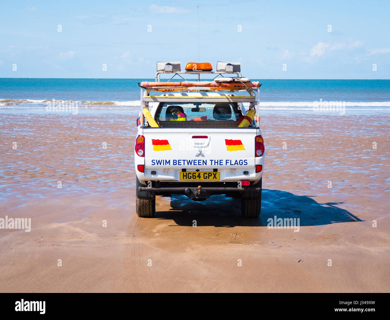 RNLI Rettungsschwimmer Pick-up LKW geparkt auf Croyde Strand in der Nähe der Brandung an einem sonnigen Tag mit blauem Himmel, Devon, England, UK Stockfoto
