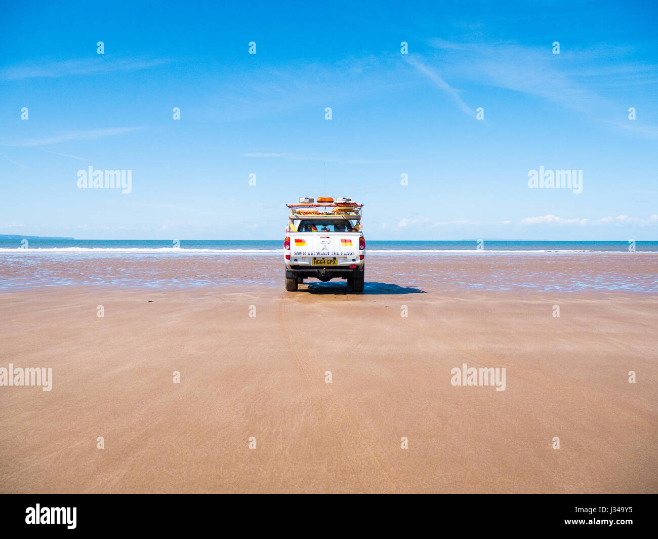 RNLI Rettungsschwimmer Pick-up LKW geparkt auf Croyde Strand in der Nähe der Brandung an einem sonnigen Tag mit blauem Himmel, Devon, England, UK Stockfoto
