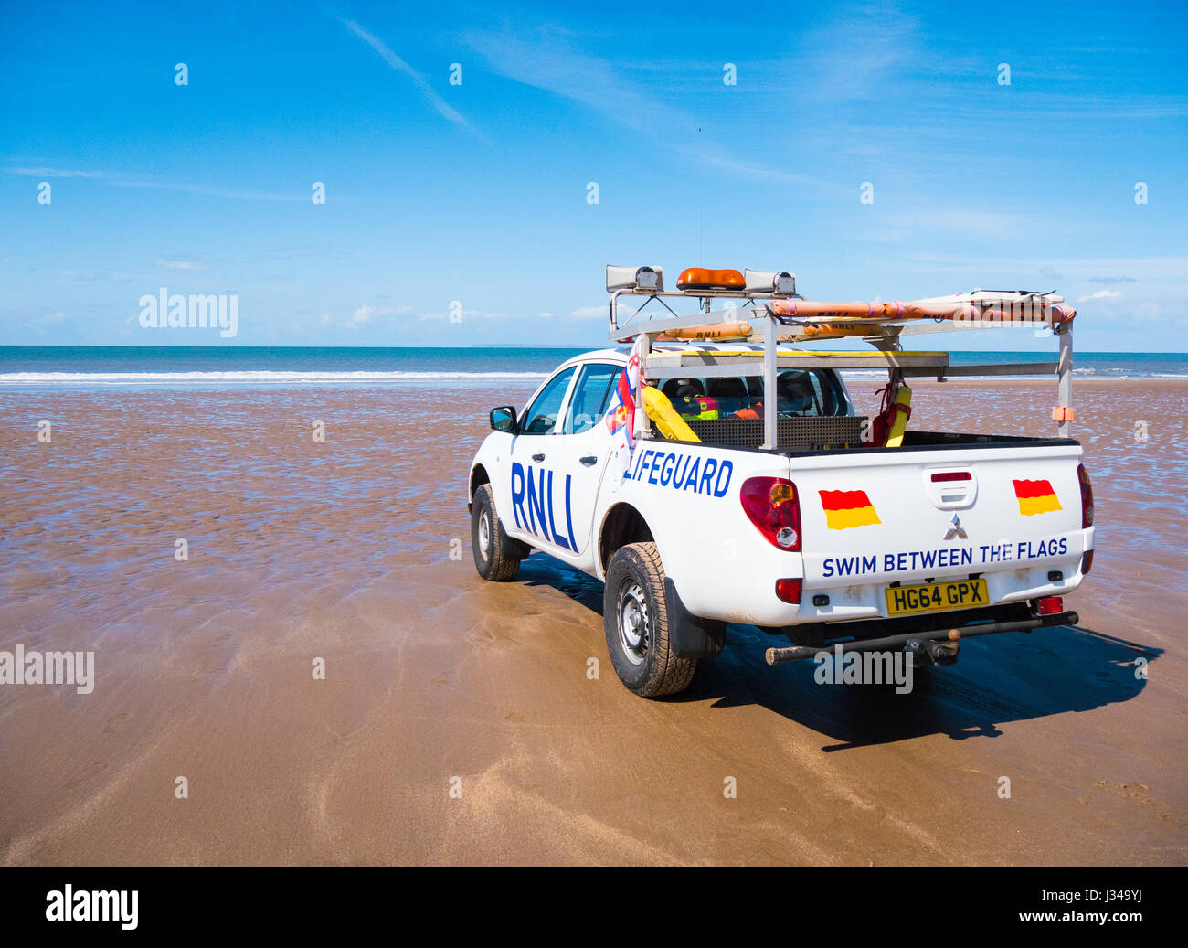 RNLI Rettungsschwimmer Pick-up LKW geparkt auf Croyde Strand in der Nähe der Brandung an einem sonnigen Tag mit blauem Himmel, Devon, England, UK Stockfoto