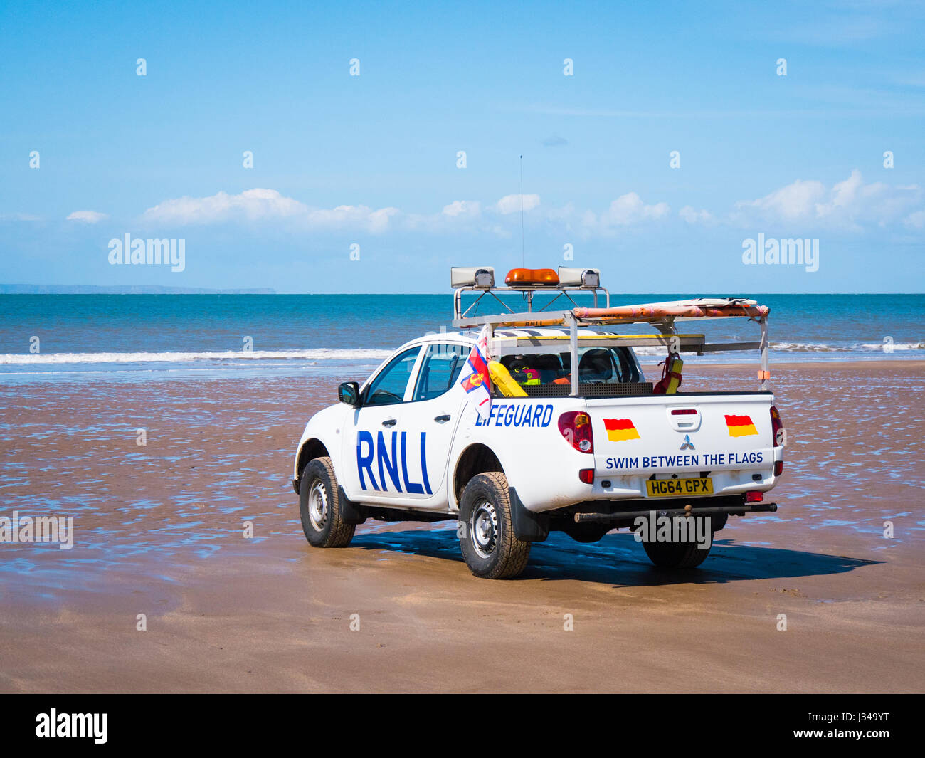 RNLI Rettungsschwimmer Pick-up LKW geparkt auf Croyde Strand in der Nähe der Brandung an einem sonnigen Tag mit blauem Himmel, Devon, England, UK Stockfoto
