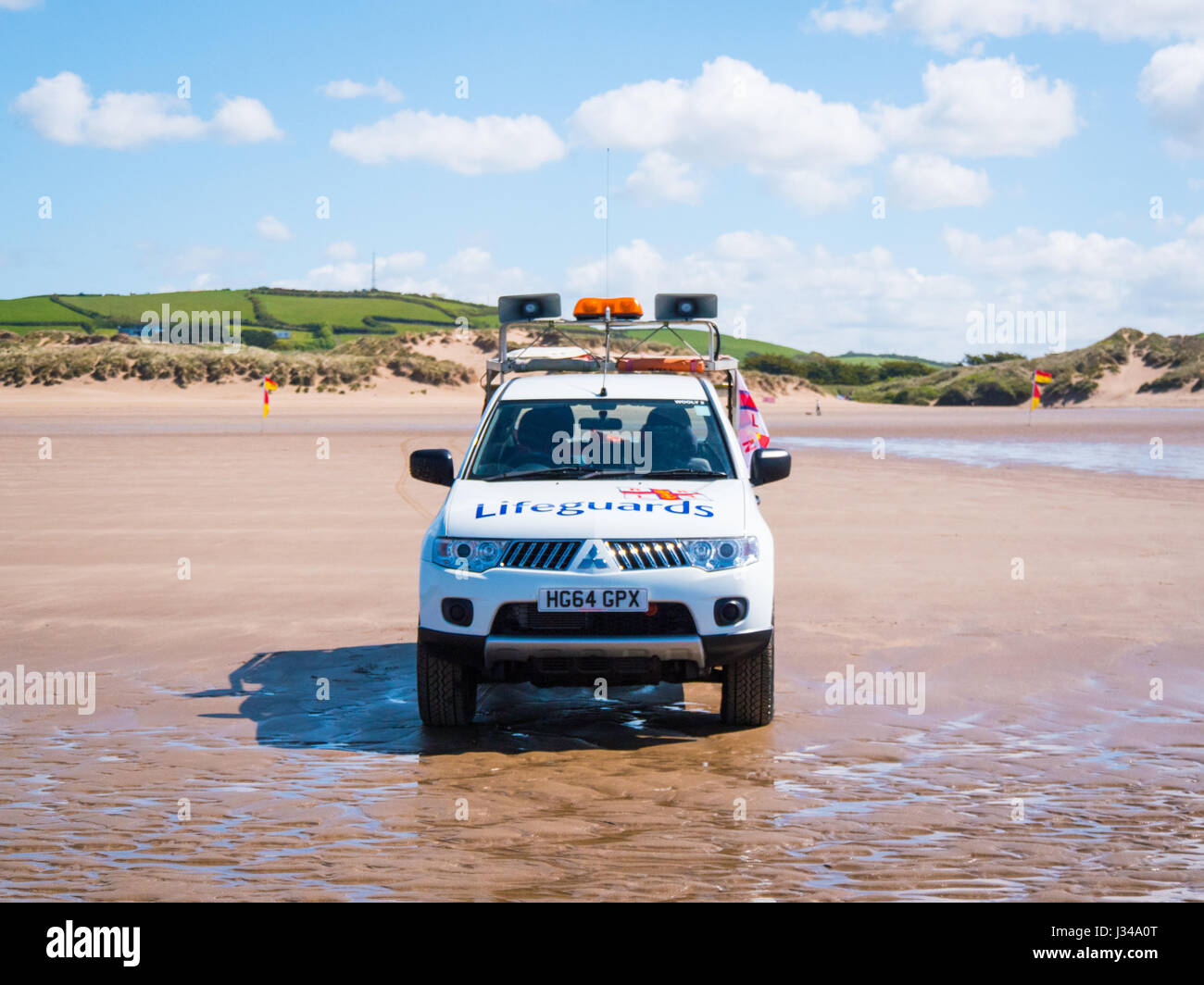 RNLI Rettungsschwimmer Pick-up LKW geparkt auf Croyde Strand in der Nähe der Brandung an einem sonnigen Tag mit blauem Himmel, Devon, England, UK Stockfoto