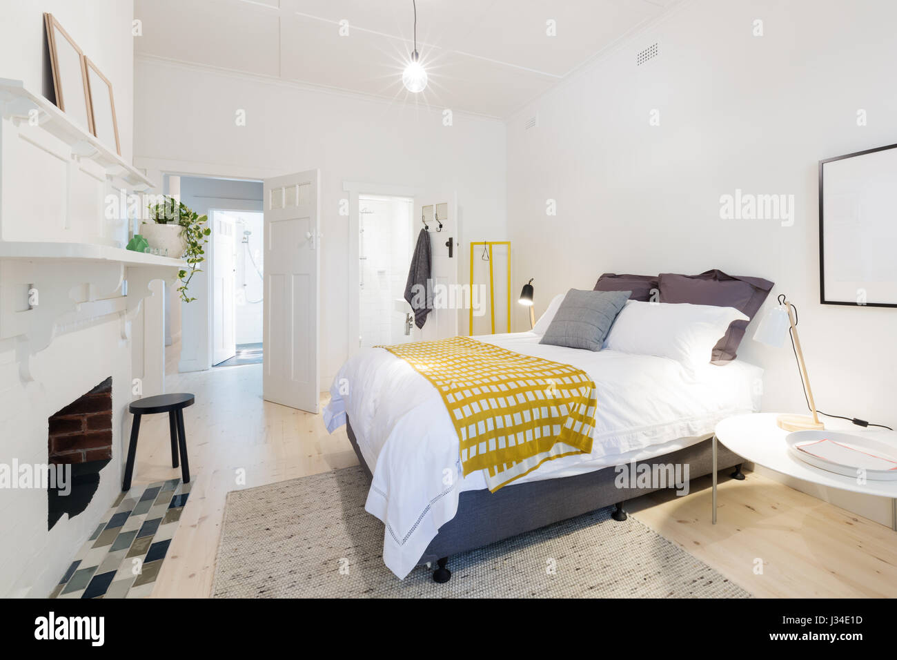 Stilvolle zeitgenössische Schlafzimmer mit eigenem Bad und gelb Dekor Akzenten Stockfoto