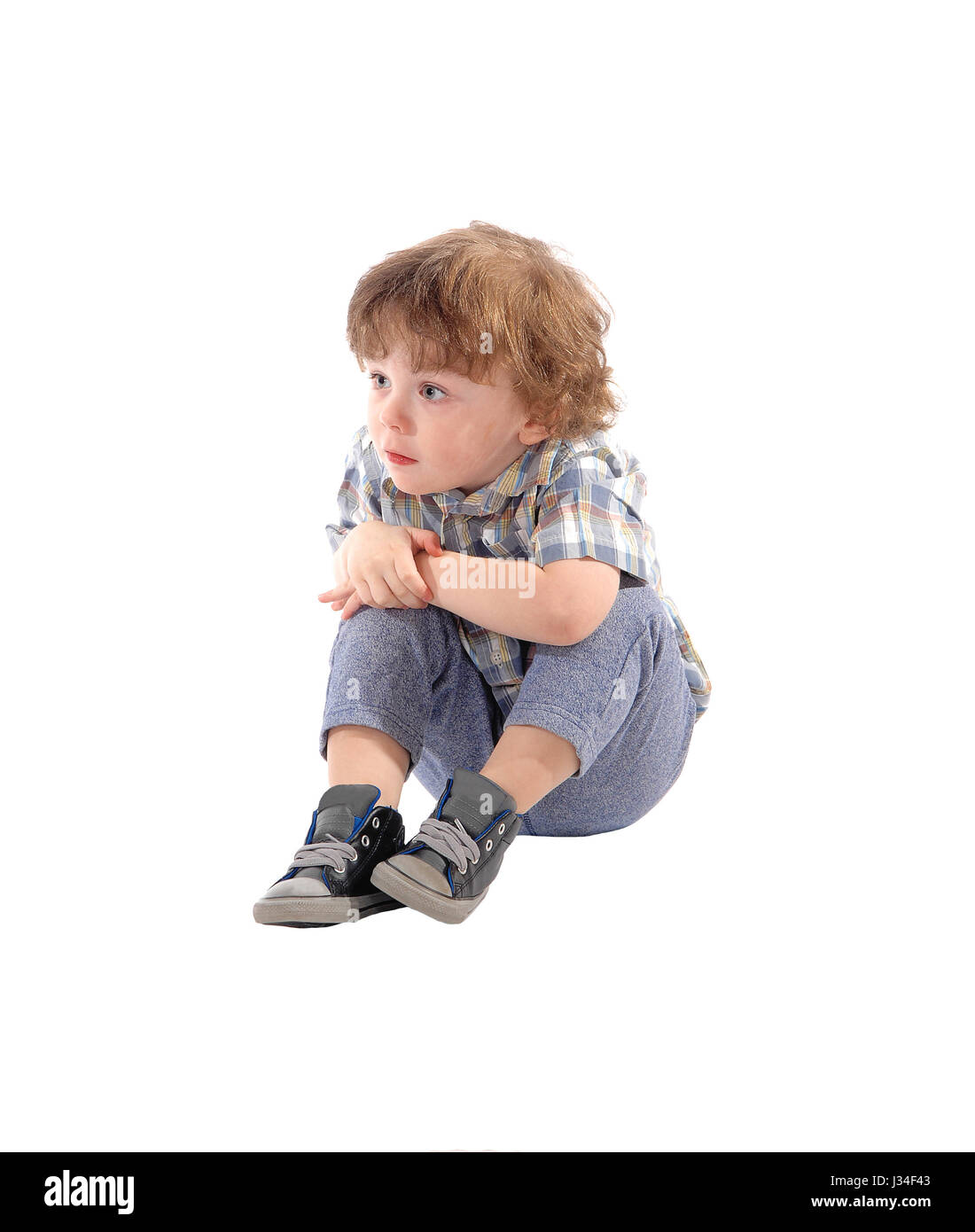 Eine Nahaufnahme Bild eines kleinen dreijährigen jungen sitzen auf dem Boden, ernst, isoliert für weißen Hintergrund. Stockfoto