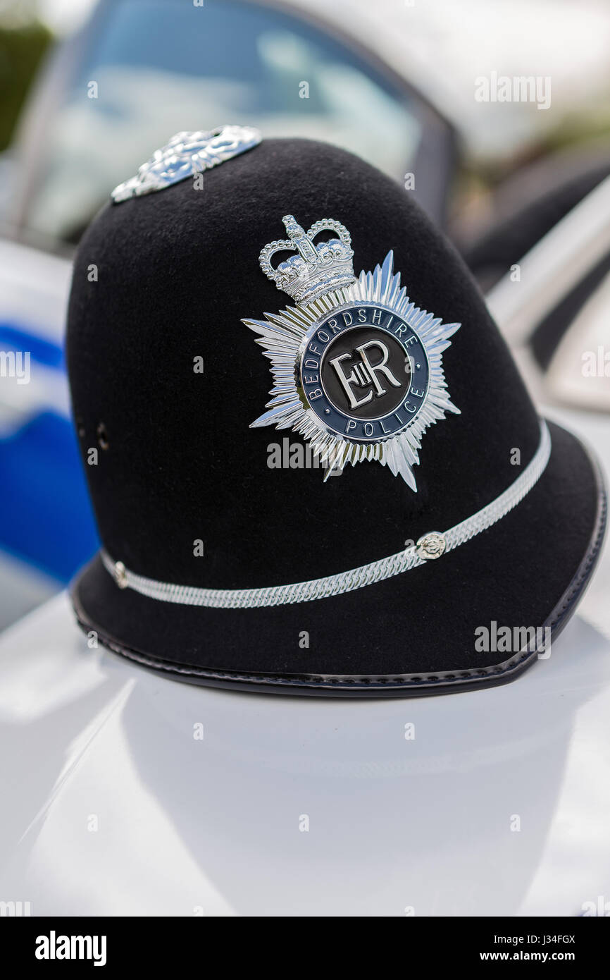 Eine Nahaufnahme von einem traditionellen Bedfordshire Polizisten Helm sitzt auf der Motorhaube von einem Vauxhall Astra Polizei Streifenwagen mit dem Abzeichen knackig scharf Stockfoto
