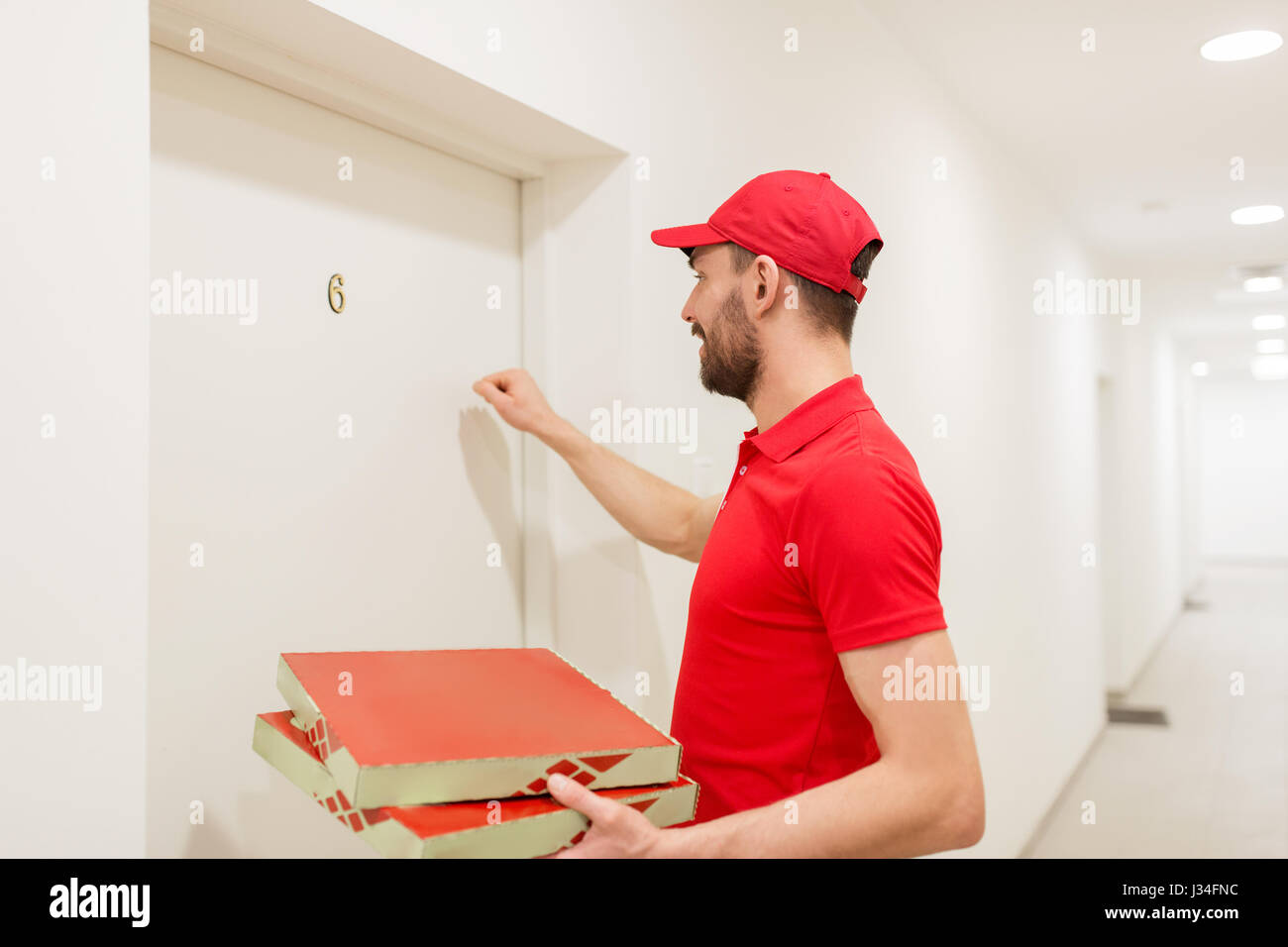 Lieferung Mann mit Pizzakartons klopfen an Tür Stockfoto