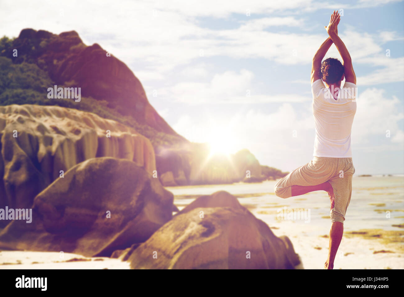Menschen, die meditieren im Yoga-Baum-Pose über Strand Stockfoto
