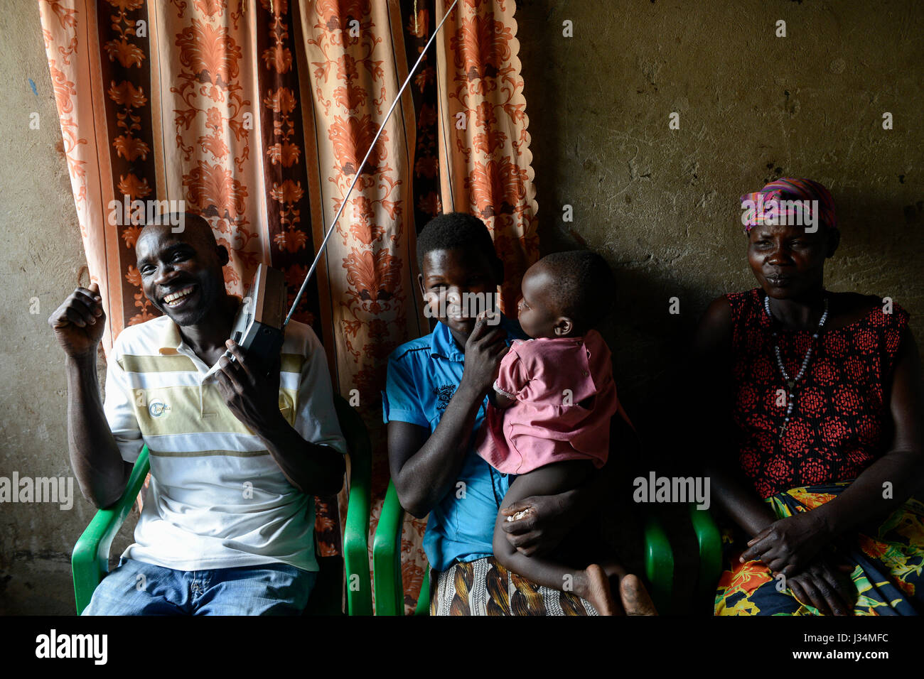UGANDA, Arua, Dorf Onduparaka, Mann und Familie hören radio Stockfoto