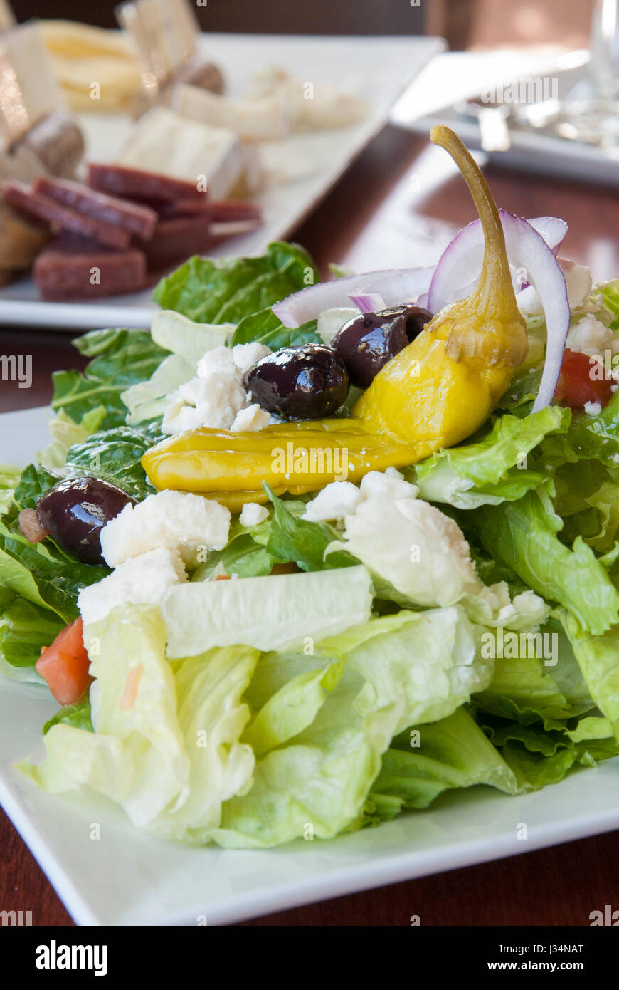 Ein frischer griechischen Salat mit Kalamata-Oliven, Feta-Käse und Peperoncino macht eine lite und gesunde Mittagessen, begleitet von einer Wurst Platte Stockfoto