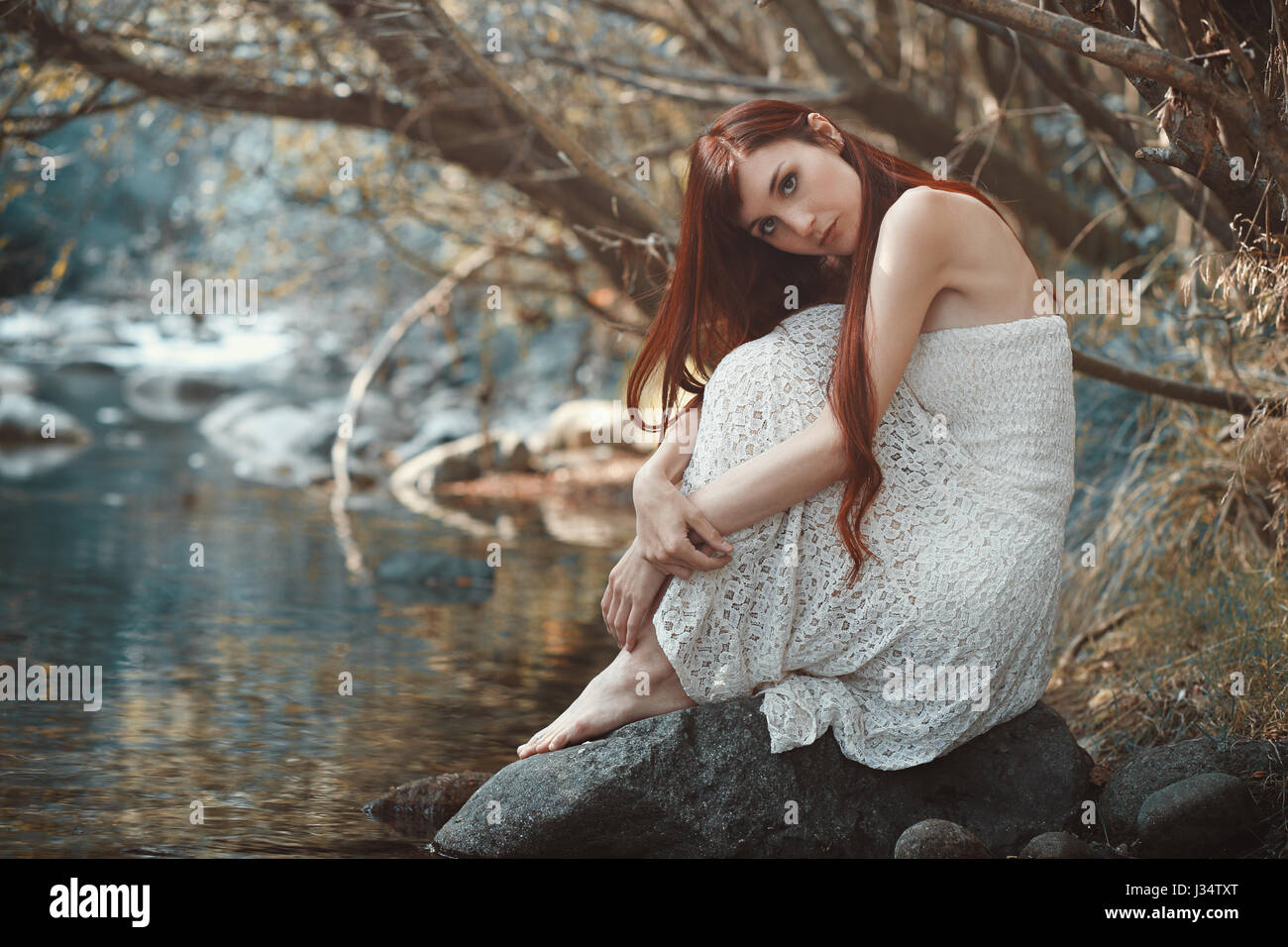 Romantische Frau posiert in der Nähe von Stream Gewässer. Stockfoto