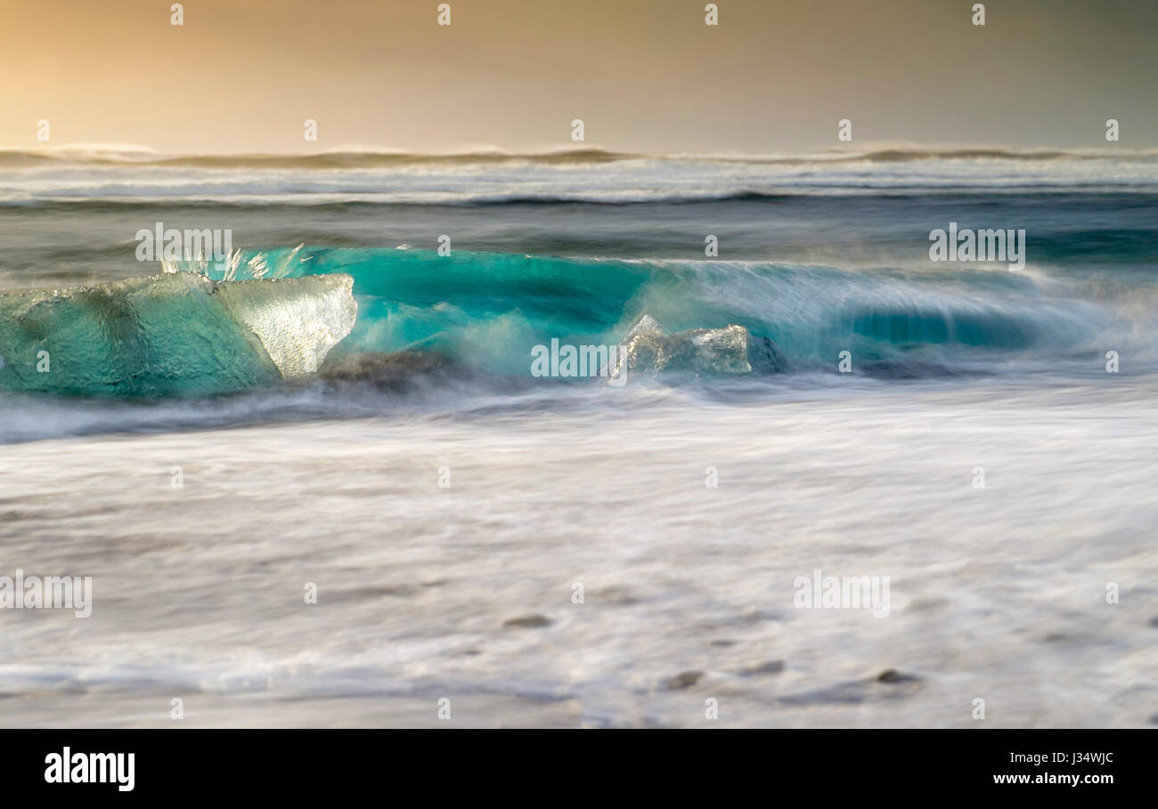 JÖKULSÁRLÓN, Island - ca. März 2015: Wellen, die in einem Eisberg am Strand in der Nähe der Jökulsárlón Lagune in Island am Rande des Vatnajök Stockfoto