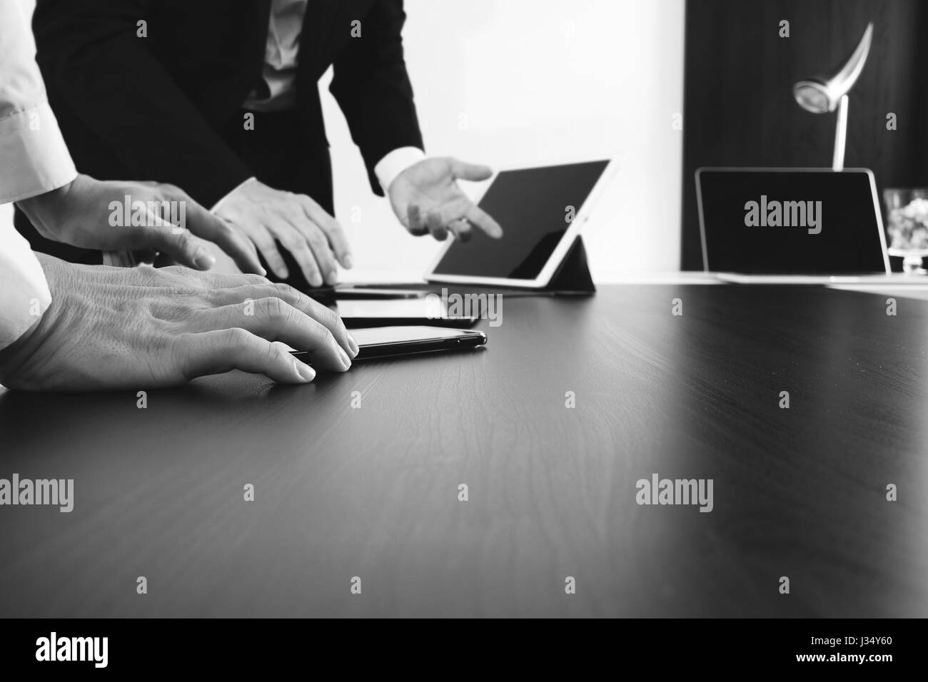 Co-Working-Team-Meeting Konzept, Geschäftsmann mit Smartphone und digitale Tablet und Laptop-Computer in modernen Büros, schwarz / weiß Stockfoto
