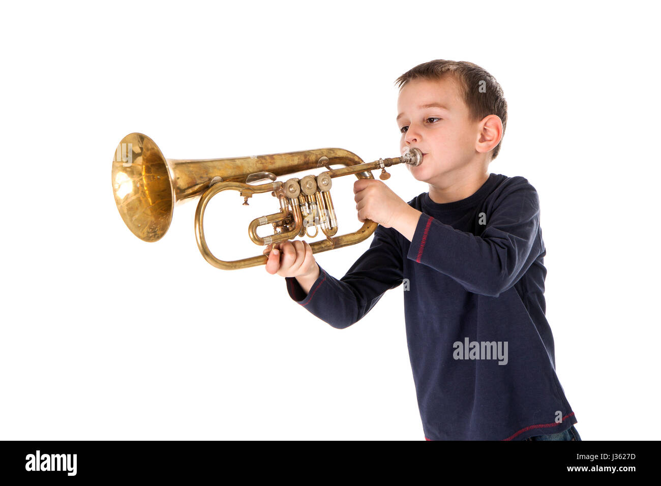 kleiner Junge bläst in eine Trompete vor weißem Hintergrund Stockfoto