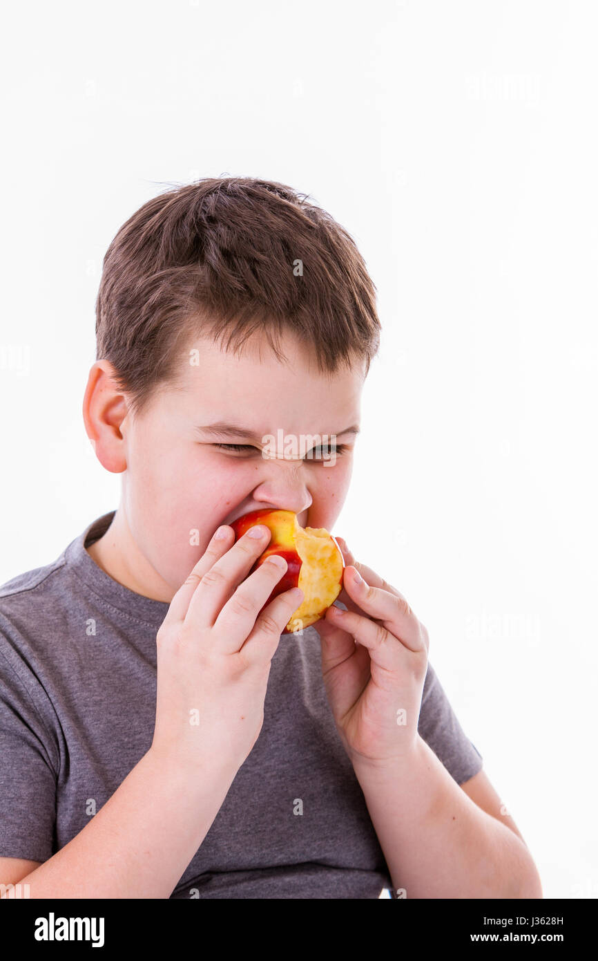 kleiner Junge mit Lebensmitteln isoliert auf weißem Hintergrund - Apfel oder ein muffin Stockfoto
