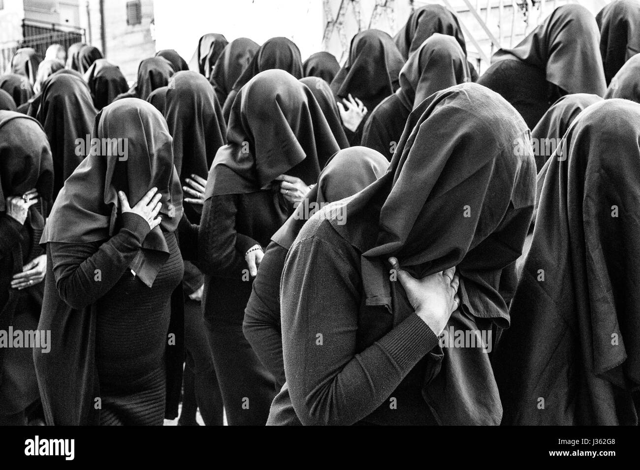 Frauen in schwarz mit dem Gesicht bedeckt von einem schwarzen Schleier Parade singen während der Prozession der Desolata, im Dorf Canosa di Puglia, Italien Stockfoto