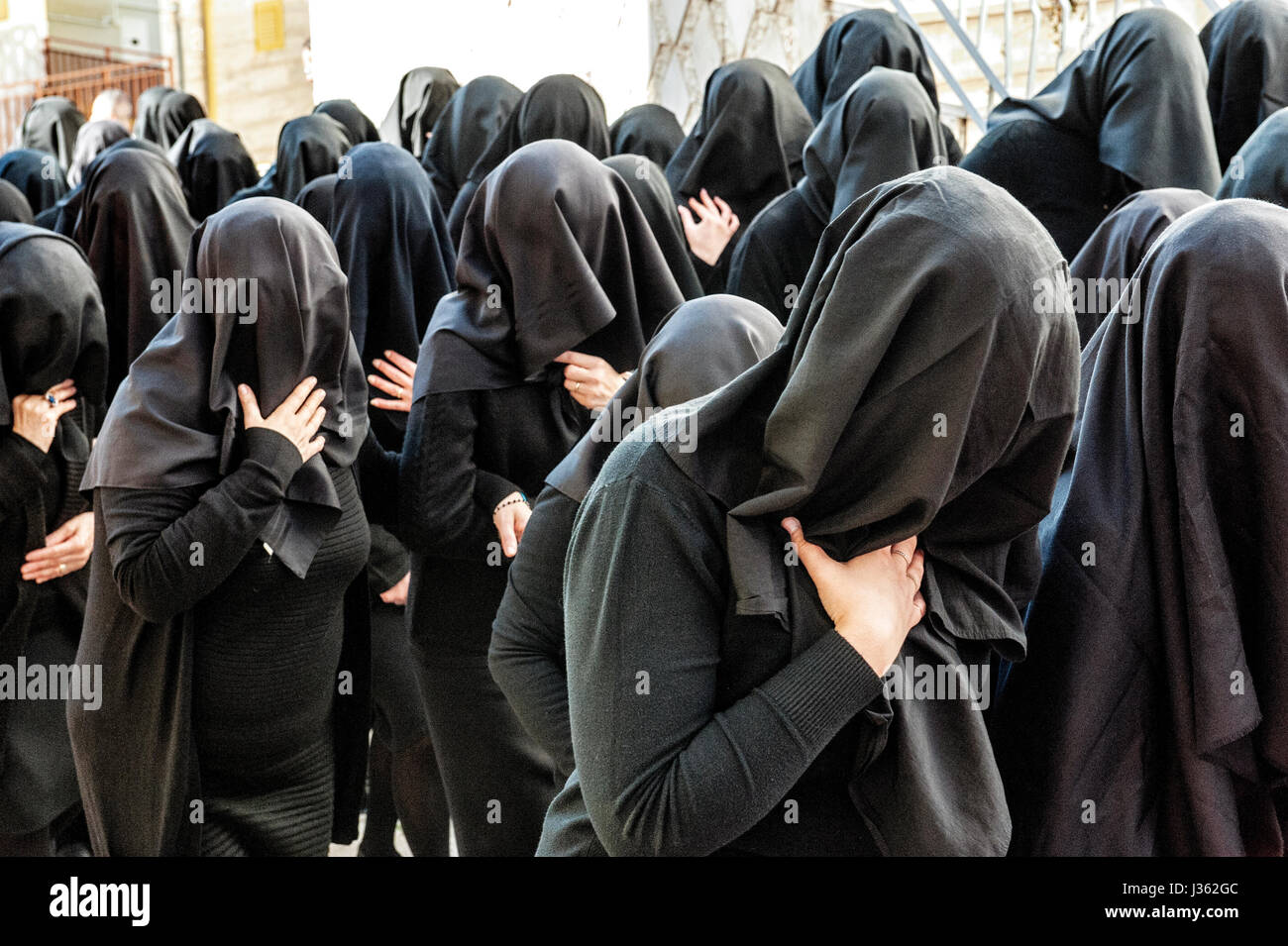 Frauen in schwarz mit dem Gesicht bedeckt von einem schwarzen Schleier Parade singen während der Prozession der Desolata, im Dorf Canosa di Puglia, Italien Stockfoto